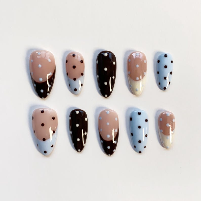 Puede incluir: Un conjunto de diez u&ntilde;as postizas en forma de almendra. Las u&ntilde;as presentan una variedad de dise&ntilde;os, incluyendo colores lisos, lunares y patrones de bloques de color. Los colores incluyen azul claro, marr&oacute;n y beige.