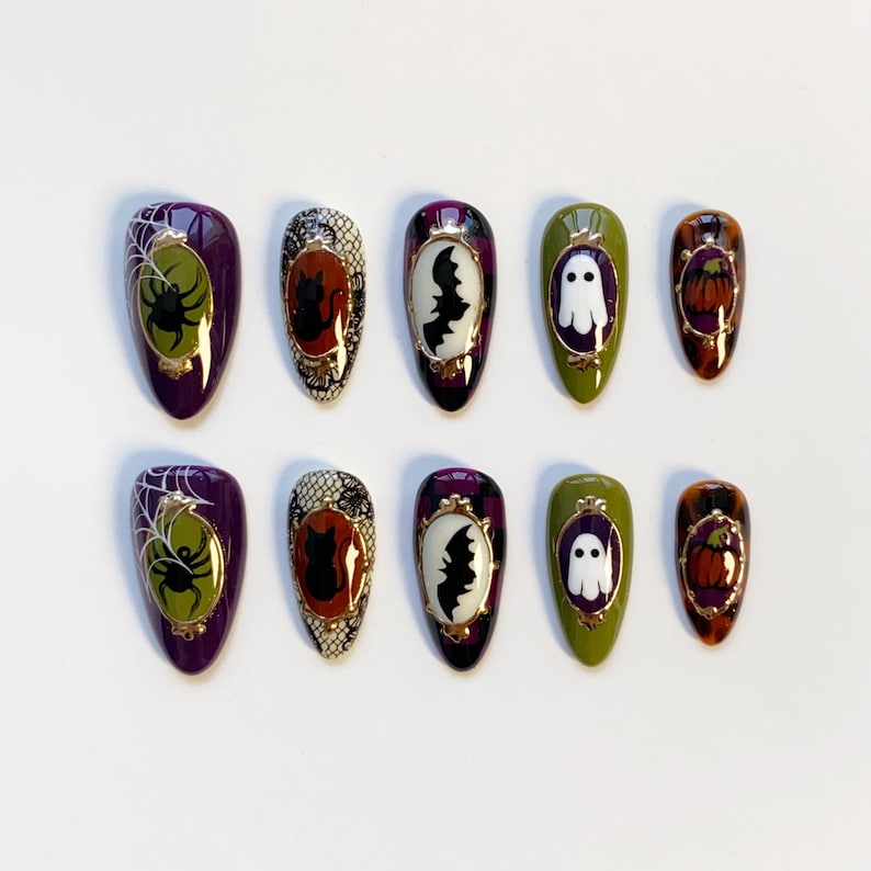 May include: A set of ten press-on nails with Halloween-themed designs. Each nail features a different design, including a spider, cat, bat, ghost, and pumpkin. The nails are oval-shaped and painted in various colors, including purple, green, and orange.