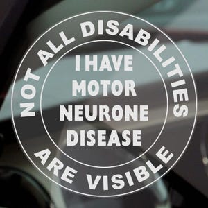May include: A circular sticker with white text on a transparent background. The text reads "NOT ALL DISABILITIES ARE VISIBLE" around the edge, with "I HAVE MOTOR NEURONE DISEASE" in the center. The sticker is likely for a vehicle.