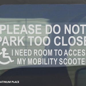 May include: White sticker with the text "PLEASE DO NOT PARK TOO CLOSE I NEED ROOM TO ACCESS MY MOBILITY SCOOTER" and a wheelchair symbol. The sticker is on a car window.