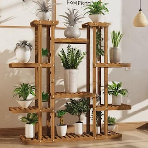 May include: A multi-tiered, wooden plant stand with multiple shelves, holding various potted plants. The stand is made of light brown wood and has a geometric design. The plants include ferns, succulents, and other greenery.