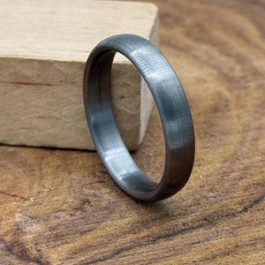 May include: A simple silver wedding band with a brushed finish.