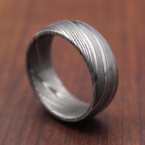 Pode incluir: Um anel de prata com um padrão único e espiral. O anel é feito de metal e tem um acabamento polido.