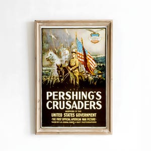 May include: Framed vintage poster titled "Pershing's Crusaders" with a sepia-toned illustration of soldiers on horseback and on foot, with American flags. The poster is in a wooden frame and features text from the United States Government.