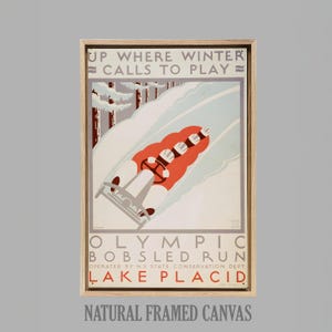 May include: A framed canvas print featuring a vintage Olympic bobsled run poster. The artwork depicts a red bobsled racing down a snowy track, with the text "UP WHERE WINTER CALLS TO PLAY" at the top and "LAKE PLACID" at the bottom.