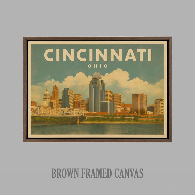 May include: A brown framed canvas print displaying a vintage illustration of the Cincinnati, Ohio skyline. The artwork includes the city name and state, with a bridge and river in the foreground, and a blue sky with clouds.