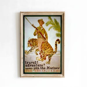 May include: Vintage framed poster with a military theme. The artwork depicts a soldier riding a spotted jaguar, holding a rifle. Text reads "travel? adventure? answer-join the Marines! ENLIST TODAY FOR 2-5 4 YEARS."