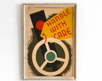 May include: Framed vintage poster with a beige steering wheel design, a black rectangle with a red circle, and a yellow tag that reads "HANDLE WITH CARE" in red. The poster has a beige background and is framed in a light-colored wood frame.