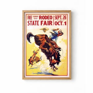 Peut inclure: Une affiche de rodéo vintage encadrée dans un cadre en bois marron. L'affiche représente un cow-boy sur un cheval sauvage, avec le texte "FREE STRAWBERRY ROAN RODEO SEPT. 26 TO OCT. 1 STATE FAIR". Le fond est jaune.