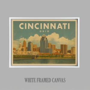 May include: A white framed canvas print displaying a vintage illustration of the Cincinnati, Ohio skyline. The artwork includes the city's name and state, with a river and bridge in the foreground. The canvas is framed in a white border.