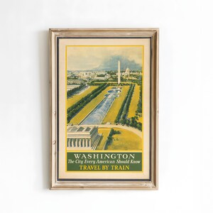 May include: Framed vintage travel poster of Washington, D.C., featuring the Washington Monument and reflecting pool. The poster has a yellow and green color scheme with the text "WASHINGTON The City Every American Should Know TRAVEL BY TRAIN".