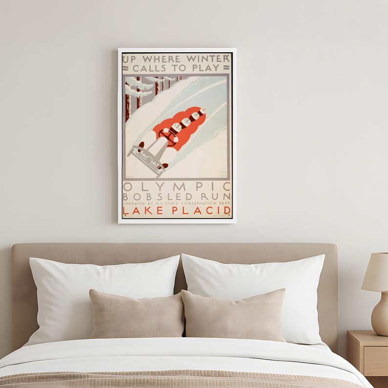 May include: A framed vintage poster with a winter sports theme. The poster features a bobsled team racing down a snowy track. Text at the top reads "UP WHERE WINTER CALLS TO PLAY." The bottom text says "OLYMPIC BOBSLED RUN LAKE PLACID."