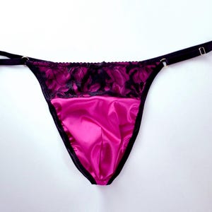Könnte beinhalten: Rosa Satin-Unterwäsche mit schwarzer Spitzenborte und verstellbaren Trägern.