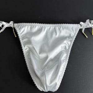 May include: White satin lingerie with gold trim and bow details.