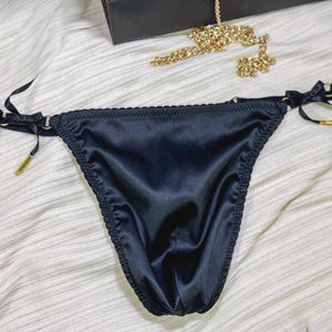 May include: Black satin lingerie with gold accents and adjustable straps.