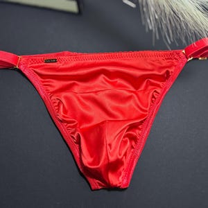 May include: Red satin underwear with a gold trim and a small black label that says "ULTIME".
