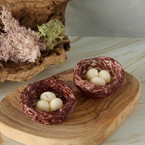 Handmade Easter nest candles with white egg-shaped wax pieces on wooden board, rustic spring decor with moss and natural textures.