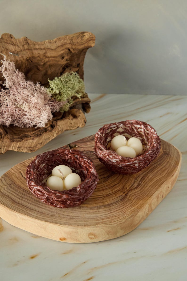 Handmade Easter nest candles with white egg-shaped wax pieces on wooden board, rustic spring decor with moss and natural textures.