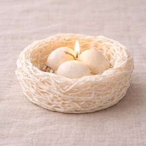 White Easter nest candle with eggs on wooden table, modern home decor