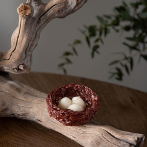 Rustic Easter table decor featuring handcrafted nest candles filled with white eggs, spring farmhouse style centerpiece.