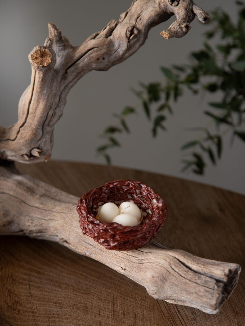Rustic Easter table decor featuring handcrafted nest candles filled with white eggs, spring farmhouse style centerpiece.