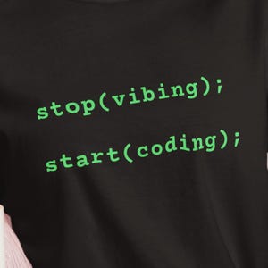 Op de afbeelding: Zwart T-shirt met groene tekst die "stop(vibing); start(coding);" zegt.