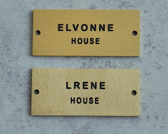 May include: Two rectangular wooden house signs. The top sign is light brown with the text "ELVONNE HOUSE" in black. The bottom sign is a lighter tan color with the text "LRENE HOUSE" in black. Each sign has two pre-drilled holes.