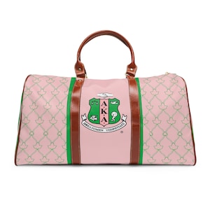 Peut inclure: Sac de sport rose avec un motif de lierre vert répété. Le panneau central présente un écusson vert et blanc avec du texte grec. Poignées et garnitures en cuir marron avec des accents verts.