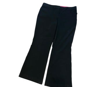 Könnte beinhalten: Schwarze Schlaghose mit klassischem Design. Die Hose hat eine taillierte Taille und weitet sich ab dem Knie. Die Hose ist aus einem einfarbigen schwarzen Stoff gefertigt.