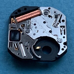 May include: Close-up of a watch movement with intricate gears, a copper coil, and the text "ORIENT WATCH CO. LTD." The watch mechanism is set against a blue background, showcasing its detailed internal components.
