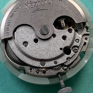 May include: Close-up of a Citizen watch movement, featuring intricate gears, screws, and the text "Citizen Watch Co." and "Twenty-One 21 Jewels." The watch mechanism is silver-toned, with a white plastic ring around the edge. The model number 8200 is also visible.
