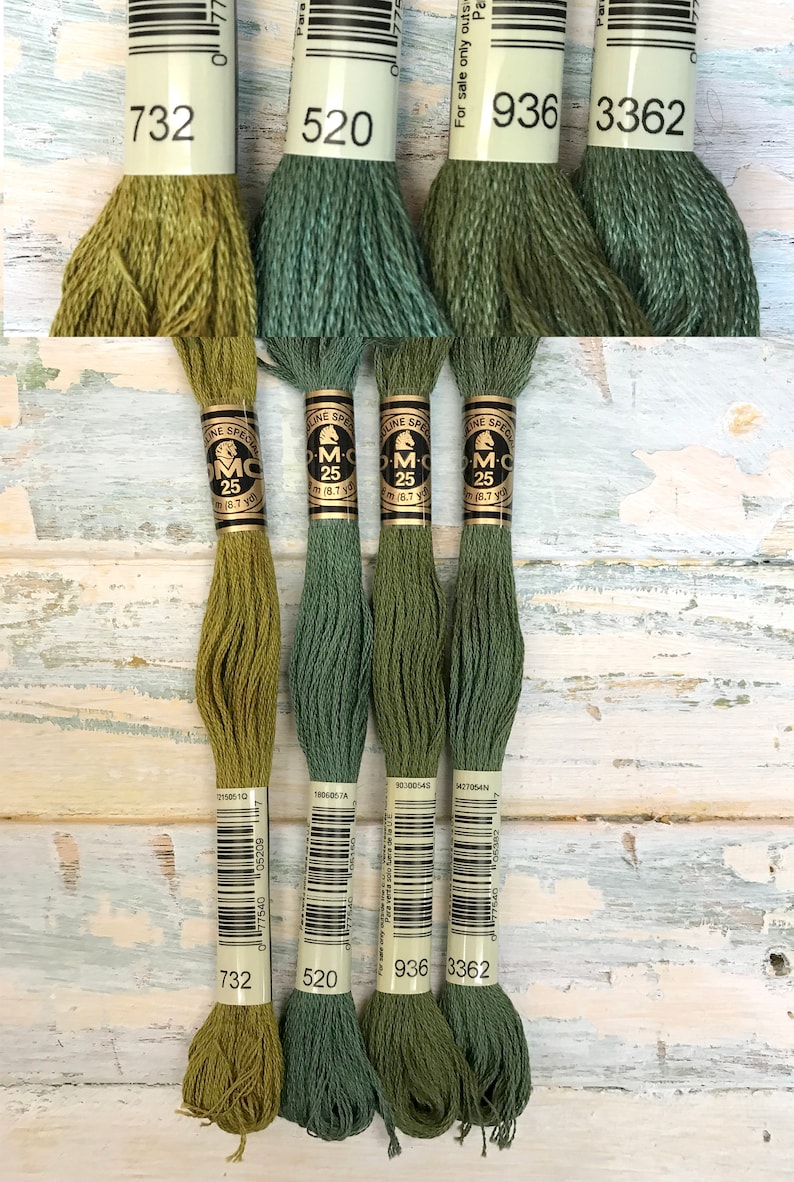May include: Four spools of DMC embroidery floss in shades of green. The spools are labeled with the DMC numbers 732, 520, 936, and 3362.