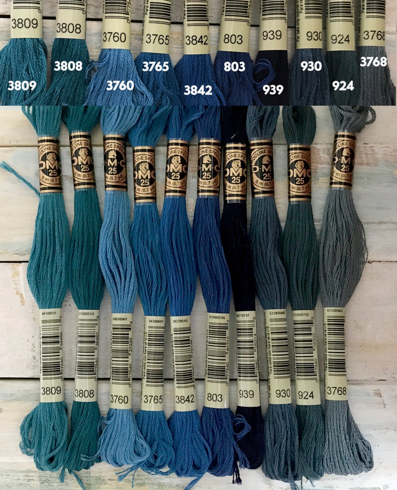 May include: A collection of 10 DMC embroidery floss spools in shades of blue and green. The spools are labeled with their DMC numbers: 3809, 3808, 3760, 3765, 3842, 803, 939, 930, 924, and 3768.
