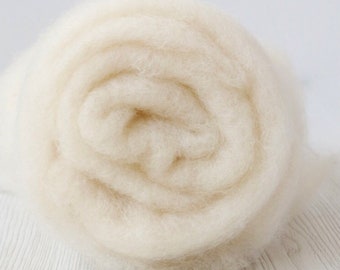 May include: A close-up of a white, fluffy ball of wool yarn. The yarn is rolled up tightly and has a soft, fuzzy texture.