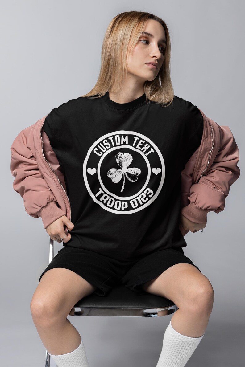 May include: Black t-shirt with a white circle graphic featuring a shamrock, hearts, and the text "CUSTOM TEXT TROOP 0123".