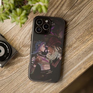 May include: Black phone case with a vibrant illustration of two figures in a face-off. One has blue hair, the other white hair and a fur collar. The case is displayed on a wooden surface.