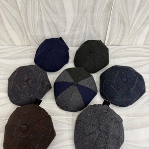 May include: A collection of eight newsboy caps in various colors and patterns. The caps are arranged in a circular pattern, showcasing different textures and designs, including herringbone and plaid. Colors range from navy and charcoal to brown and gray.