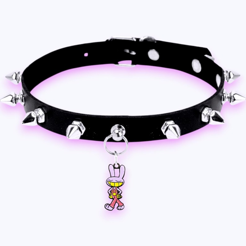 May include: A black choker collar featuring a series of silver-toned metal spikes along the band. The collar includes an adjustable buckle closure with silver-toned eyelets and a dangling charm depicting a cartoon rabbit wearing pink overalls.