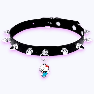 May include: Black leather choker necklace with silver-colored spikes and a small Hello Kitty charm. The choker has a metal clasp and a ring for the charm. The Hello Kitty charm is white with a red bow and blue clothing.
