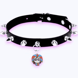 May include: A black choker necklace featuring silver-toned metal spikes arranged along the band. The choker includes a central silver ring holding a small, colorful enamel charm depicting a cartoon character wearing a jester hat in red and blue.