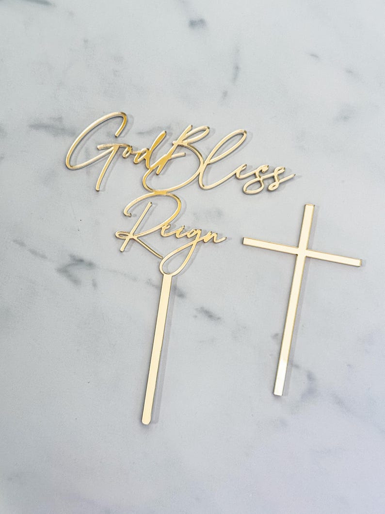 May include: Gold cake topper with the words "God Bless Reign" and a cross. The topper is perfect for a baptism or christening.