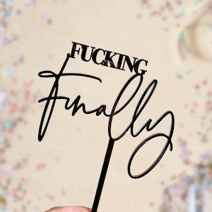 May include: Black acrylic cake topper with the text "FUCKING finally" in a cursive font.