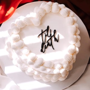 Puede incluir: Pastel blanco en forma de corazón con glaseado blanco y las palabras "Till Death" escritas en glaseado negro.