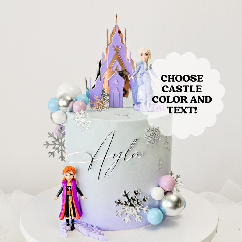 May include: A purple and blue ombre cake decorated with silver snowflakes, white and blue balls, and two Frozen figurines. The cake is topped with a purple castle cake topper and the name "Ayla" is written in silver script. The text "CHOOSE CASTLE COLOR AND TEXT!" is written in a white speech bubble.