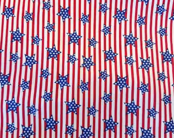 May include: Fabric with a patriotic design featuring blue stars on a white background, interspersed with red vertical stripes. The stars have a white dotted pattern, creating a classic American flag aesthetic.