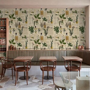 May include: A restaurant interior with a botanical wallpaper featuring illustrations of plants and bottles. The wallpaper is cream-colored with green and brown accents. There are four tables with chairs in the foreground, and a wooden shelf with jars and bottles on the left side of the image.