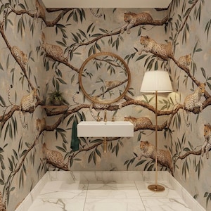 May include: A bathroom with a distinctive wallpaper design showing leopards on tree branches with green leaves. The room features a white sink, a gold-framed mirror, and a floor lamp with a white shade. The floor is white marble.