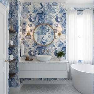 Op de afbeelding: Een badkamer met blauw en wit behang met zeemeermintthema. De kamer heeft een witte wastafel met een ronde spiegel, een witte wastafel en een wit bad. Gouden armaturen en witte gordijnen maken de inrichting compleet.