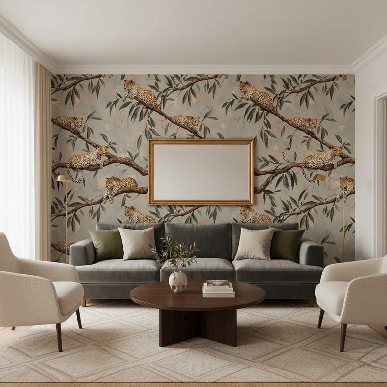 K&ouml;nnte beinhalten: Ein Wohnzimmer mit grauem Sofa, zwei cremefarbenen Sesseln und einem runden Couchtisch aus Holz. Der Blickfang ist eine Wand mit Tapeten, die Leoparden auf &Auml;sten zeigen, erg&auml;nzt durch einen goldgerahmten Spiegel.