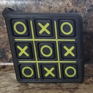 May include: Two black tic-tac-toe game boards with different colored markings. One board has yellow 'O's and green 'X's. The other board has red 'O's and orange 'X's.
